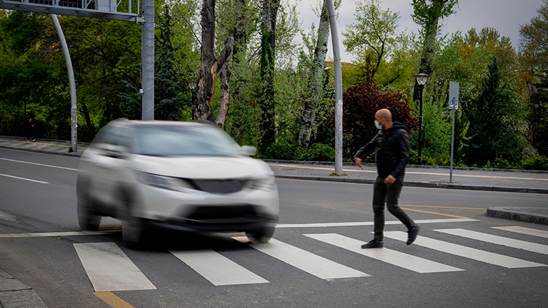 Pedestrian walking on zebra crossing and a driving car failing to stop in blurred motion.